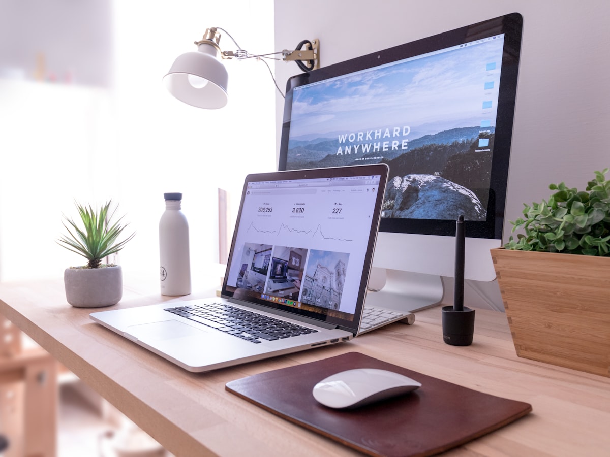 A tidy desk with a laptop and monitor, both showing content dashboards, in daylight.