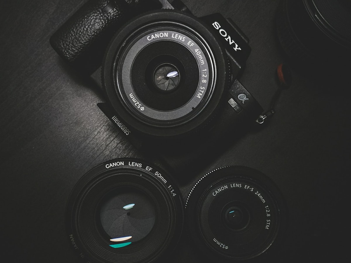 A camera body and two lenses laid out on a dark surface.