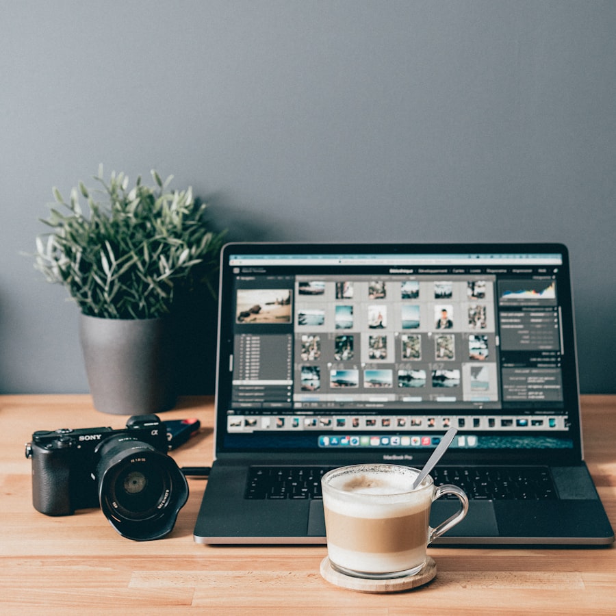 A mirrorless camera beside a laptop showing a photo library.
