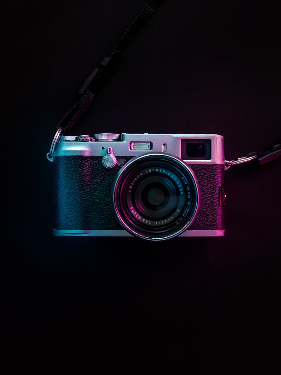 A compact camera lit in blue and magenta.